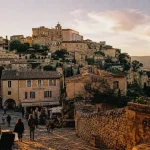 Gordes, plus beaux villages du monde : vue au coucher du soleil sur pierres blondes et ruelles